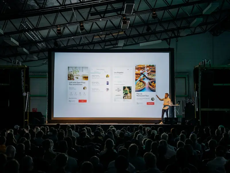 A speaker presenting data on screen to an engaged audience